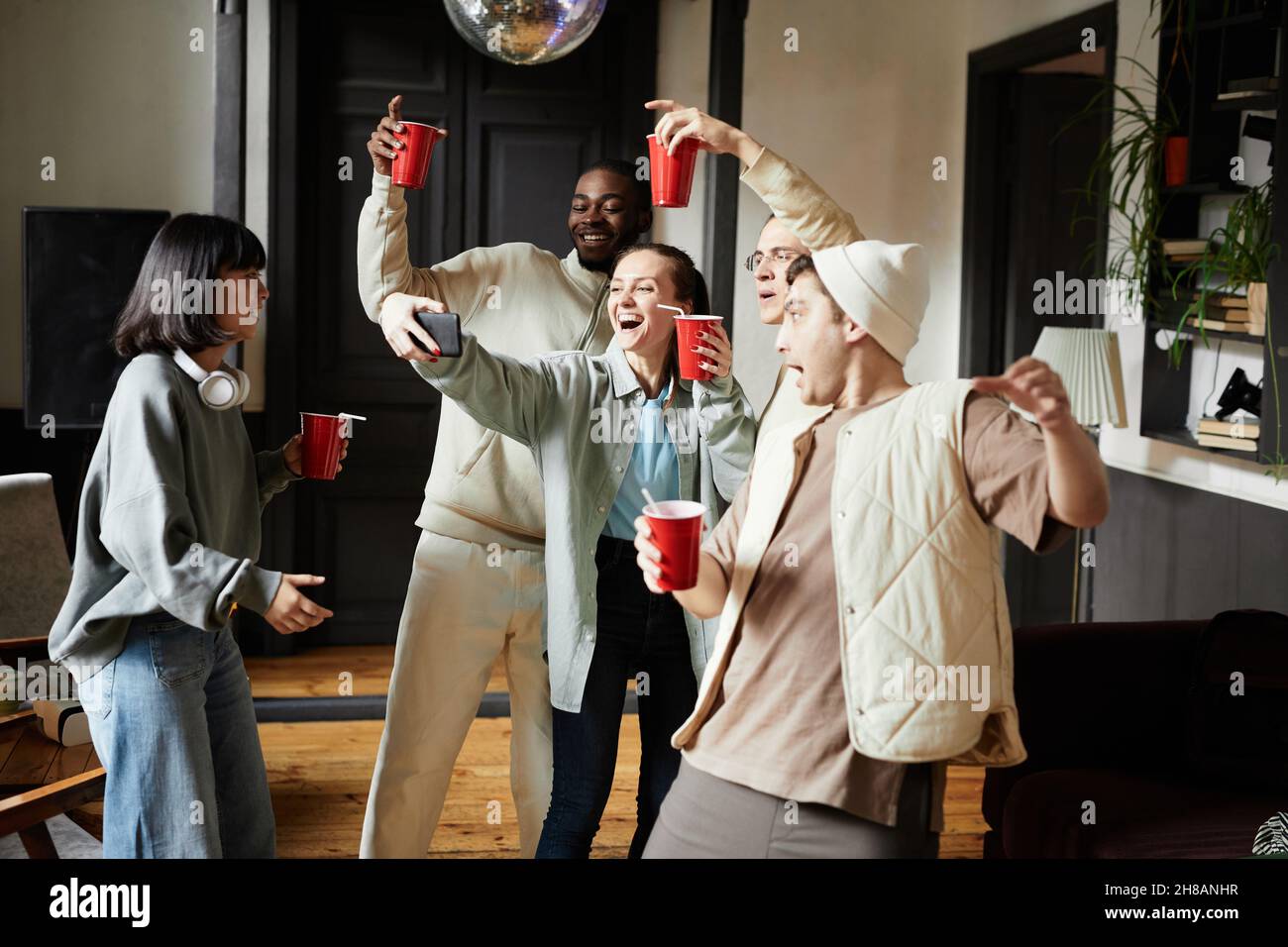Gruppo di adolescenti con bevande che ballano e si divertono durante una festa Foto Stock