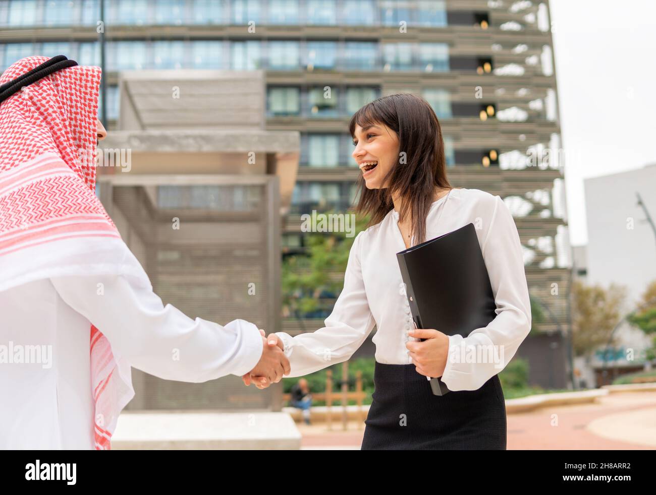 Due felice soddisfatto multirazziale business partner uomo e donna scuotendo le mani dopo il successo delle trattative a riunione, giovane donna d'affari caucasica saluto arabo cliente maschio con sorriso sulla faccia Foto Stock