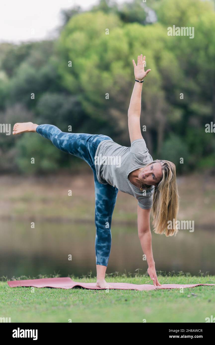 Donna che fa la posa triangolare di yoga in un parco Foto Stock