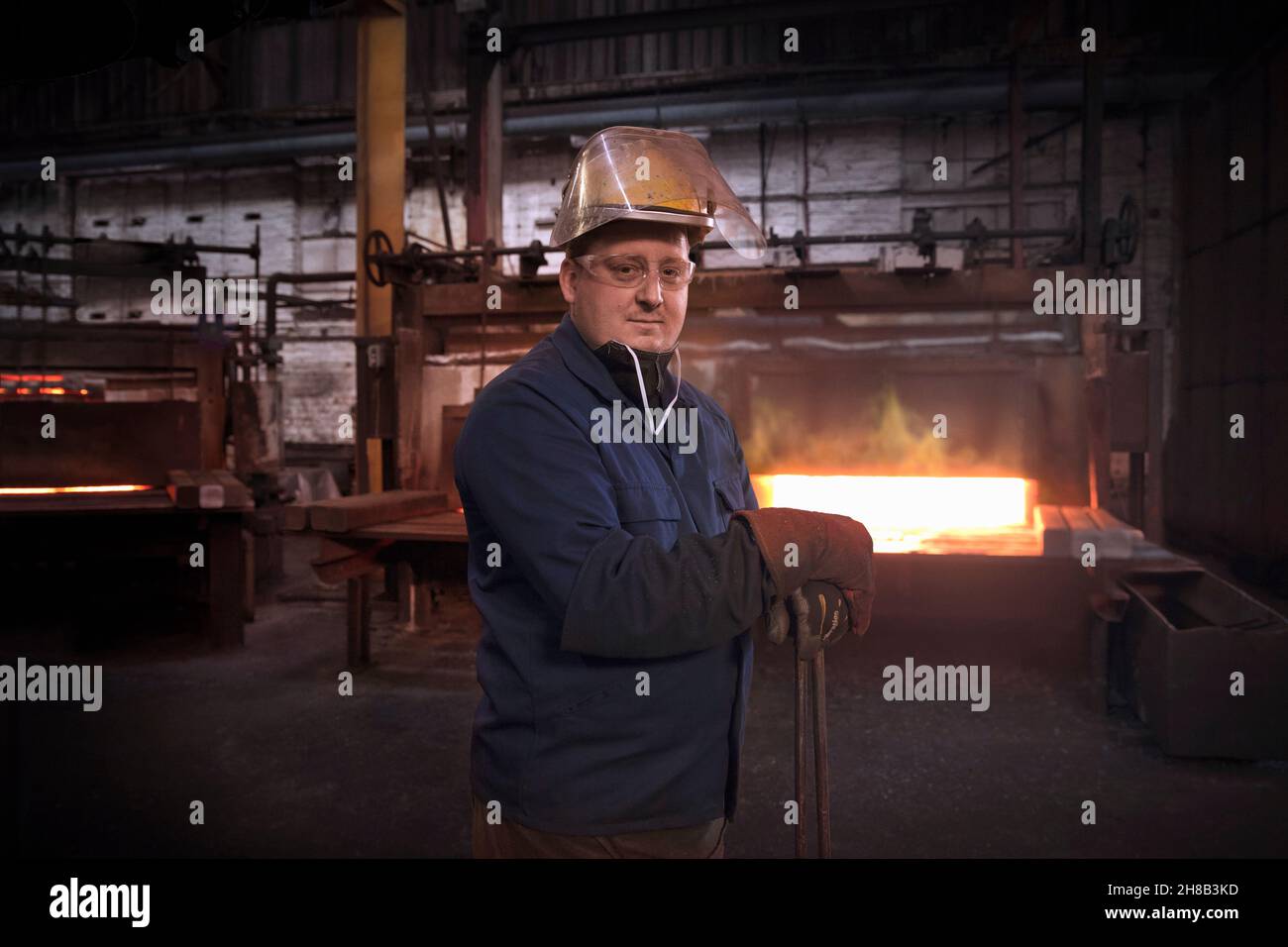 Forge Worker, secondo al comando del controllo del martello o 'antimanomissione' nella zona di preformatura della forgiatura con un set di pinze industriali quando la porta del forno è chiusa Foto Stock