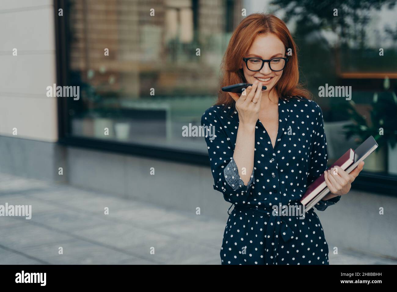 La donna effettua registrazioni vocali online per l'invio di messaggi audio pose all'aperto Foto Stock