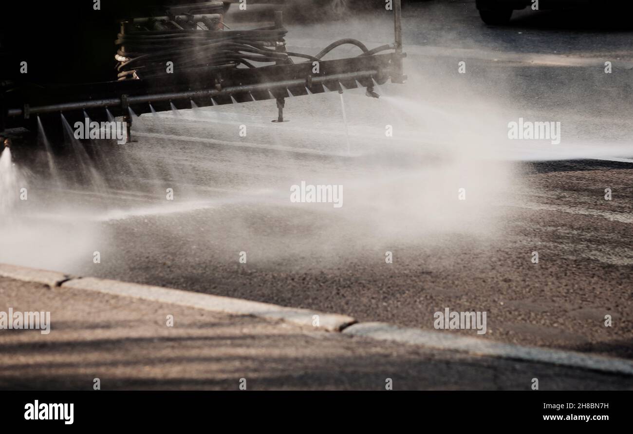 Pulendo lavatrici lavatrici lavatrici la strada delle strade della città con acqua nebulizzata, gruppo di annaffiatrici comunali lavano asfalto, Foto Stock