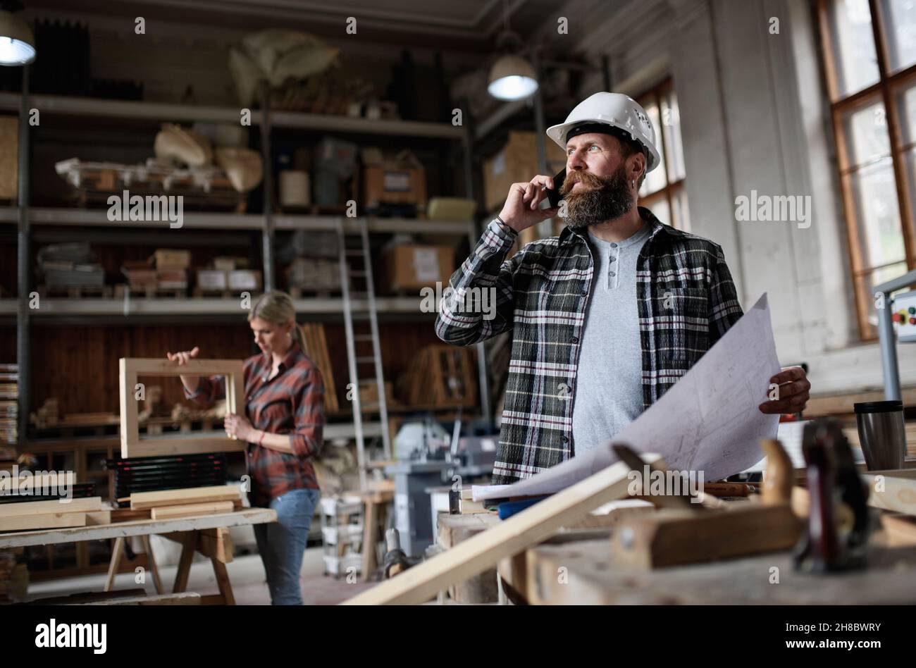 Vista ad angolo basso del carpentiere maschio maturo che guarda i piani di blueprints in officina carpenteria. Foto Stock