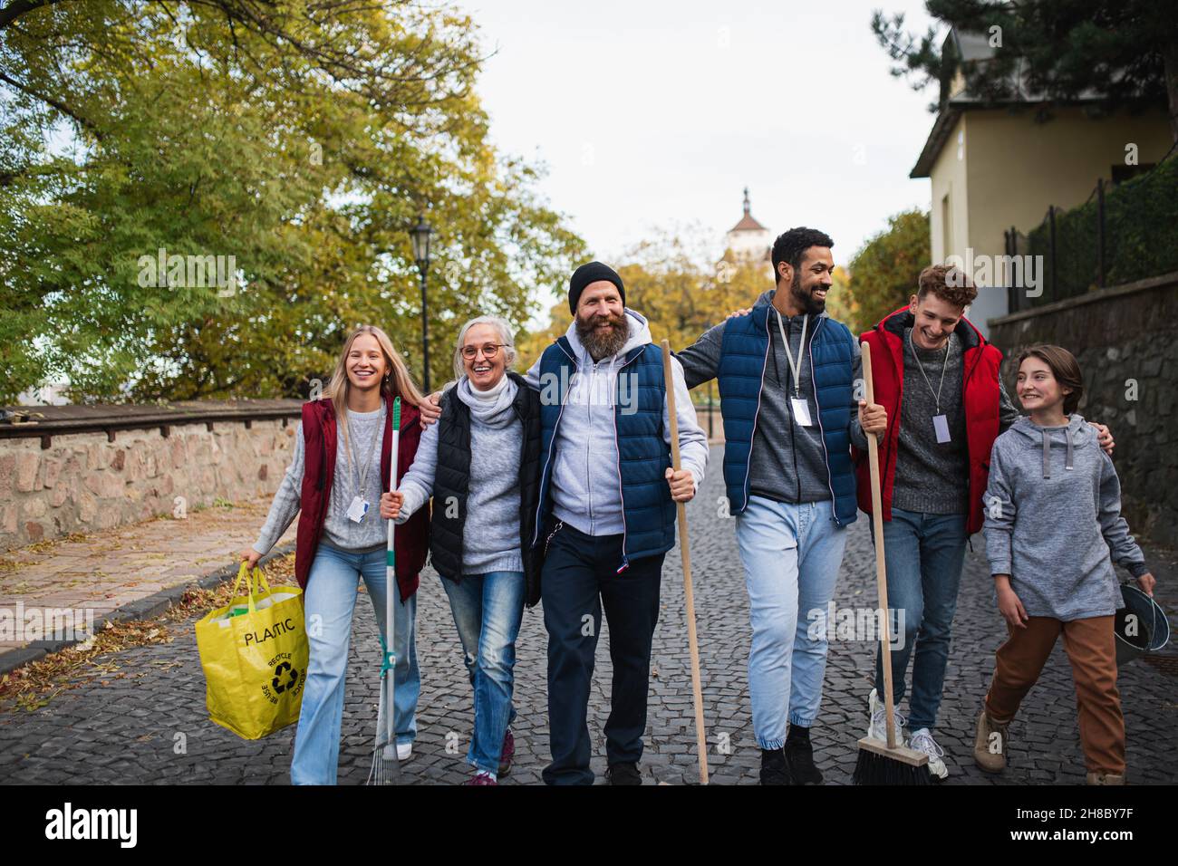Un gruppo di volontari felici che camminano con gli strumenti per pulire la strada, concetto di servizio comunitario Foto Stock