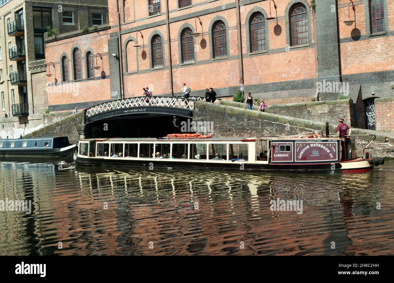 Il Waterbus 'Gardenia' passa di fronte ad un vecchio magazzino, sul canale Regents, appena oltre, Camden Lock Foto Stock