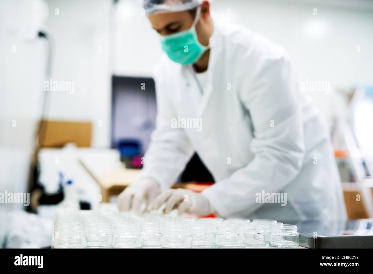 Tecnico farmaceutico maschile. Uomo che lavora con bicchieri da laboratorio e vetreria. Scienziato che conduce esperimento in laboratorio Foto Stock