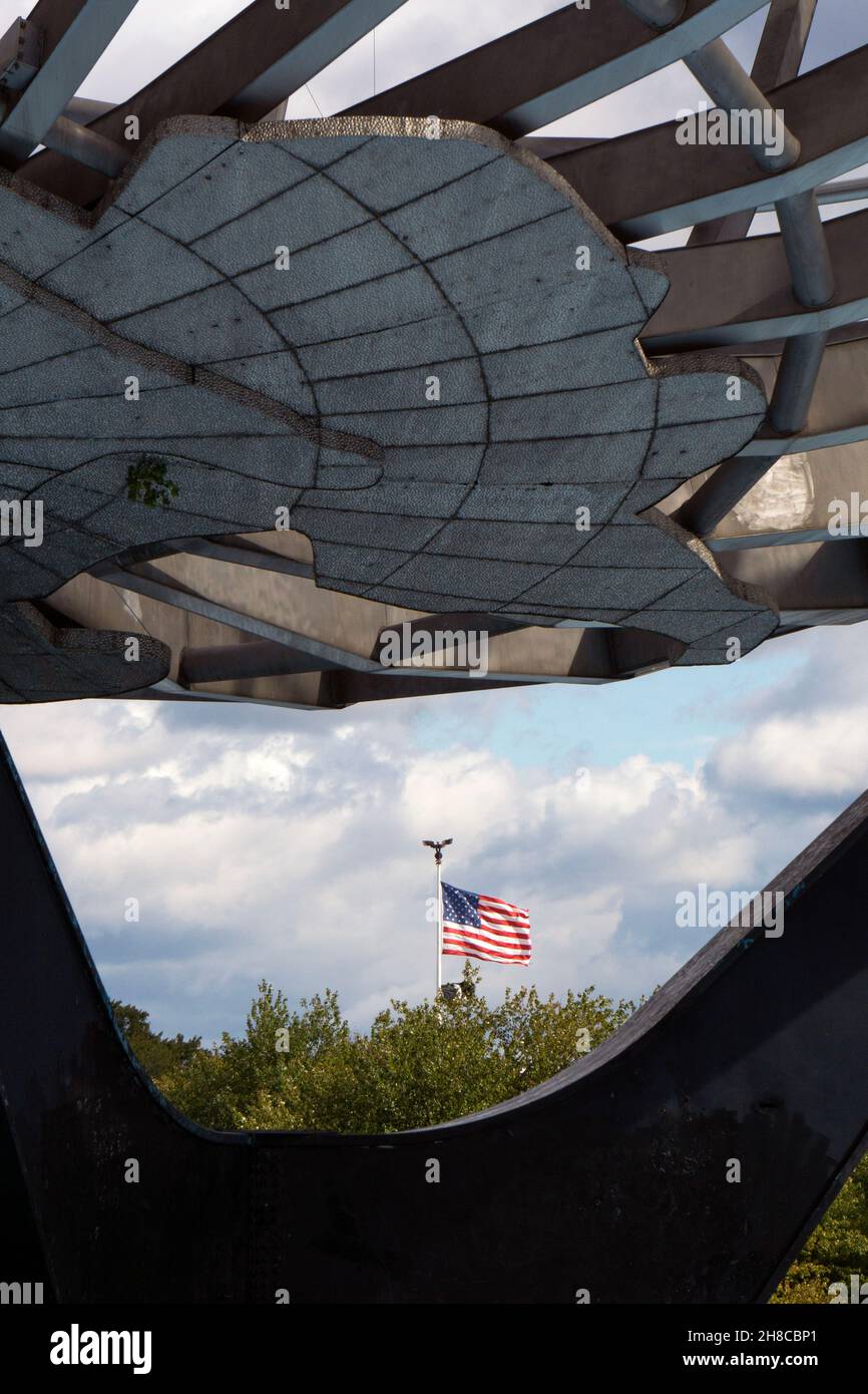 Una vista insolita di una bandiera americana che soffia nel vento come visto attraverso la base dell'Unisphere in Flushing Meadows Corona Park, Queens, New York. Foto Stock