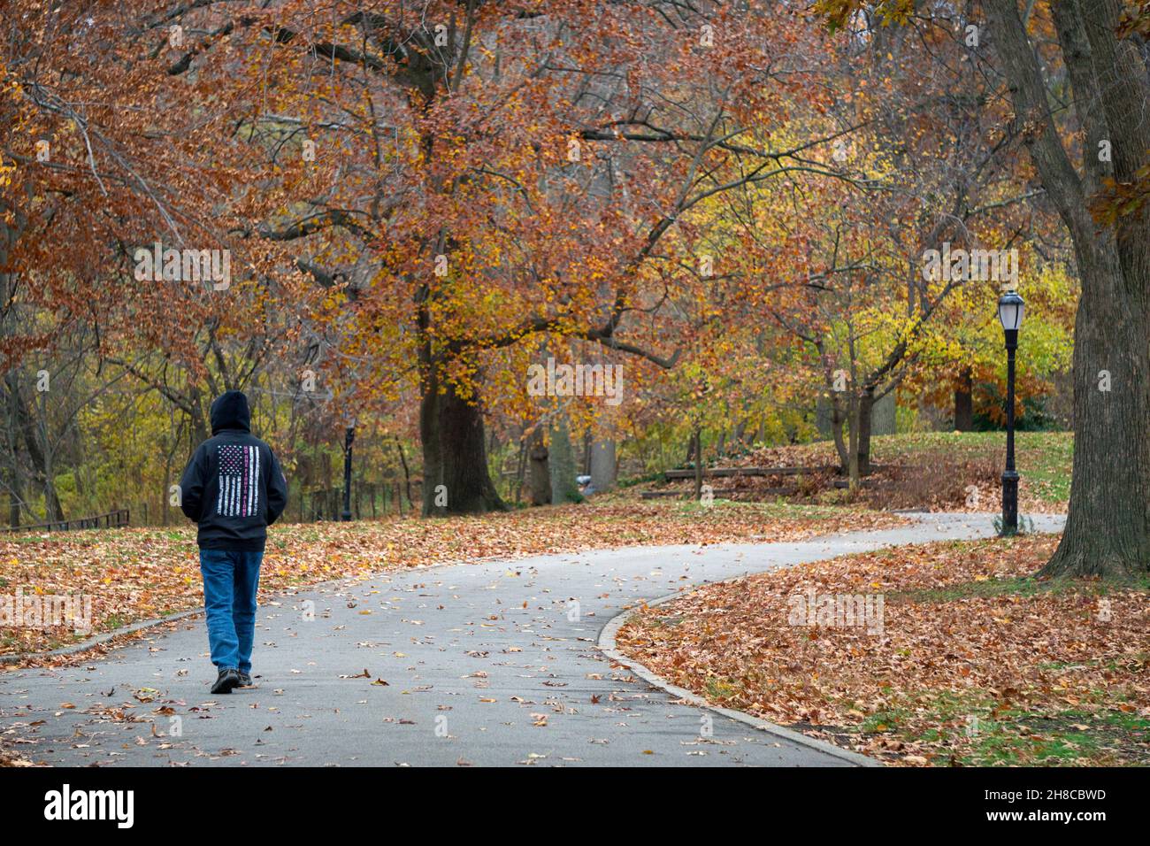 Un uomo anonimo che indossa una felpa con cappuccio e una bandiera americana rovesciata su una camminata di esercitazione in un pomeriggio coloratissimo di autunno. A Queens, New York Foto Stock