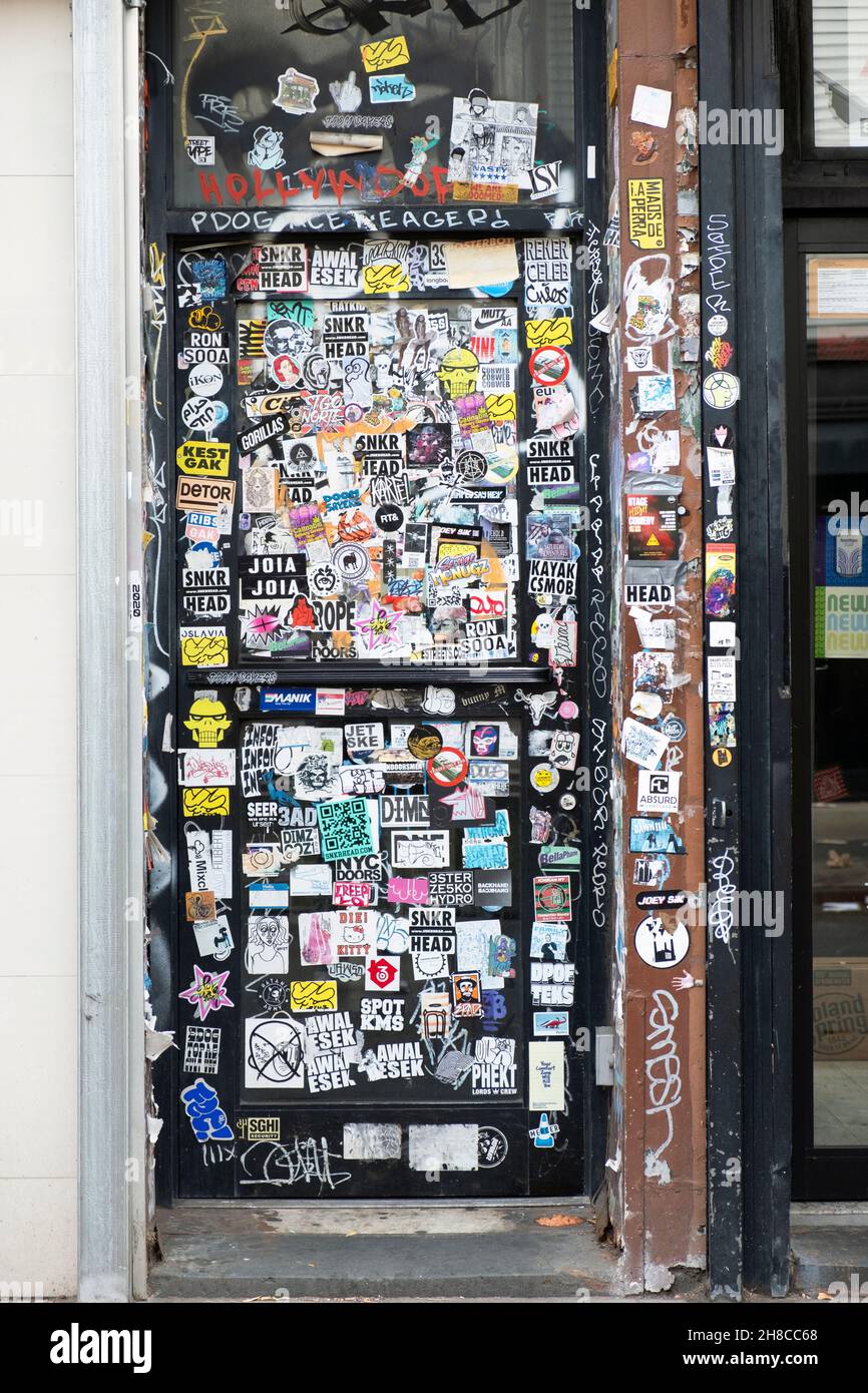 Una porta completamente coperta di adesivi, Street art, graffiti e tag. Su Bedford Ave. A Williamsburg, Brooklyn, New York. Foto Stock