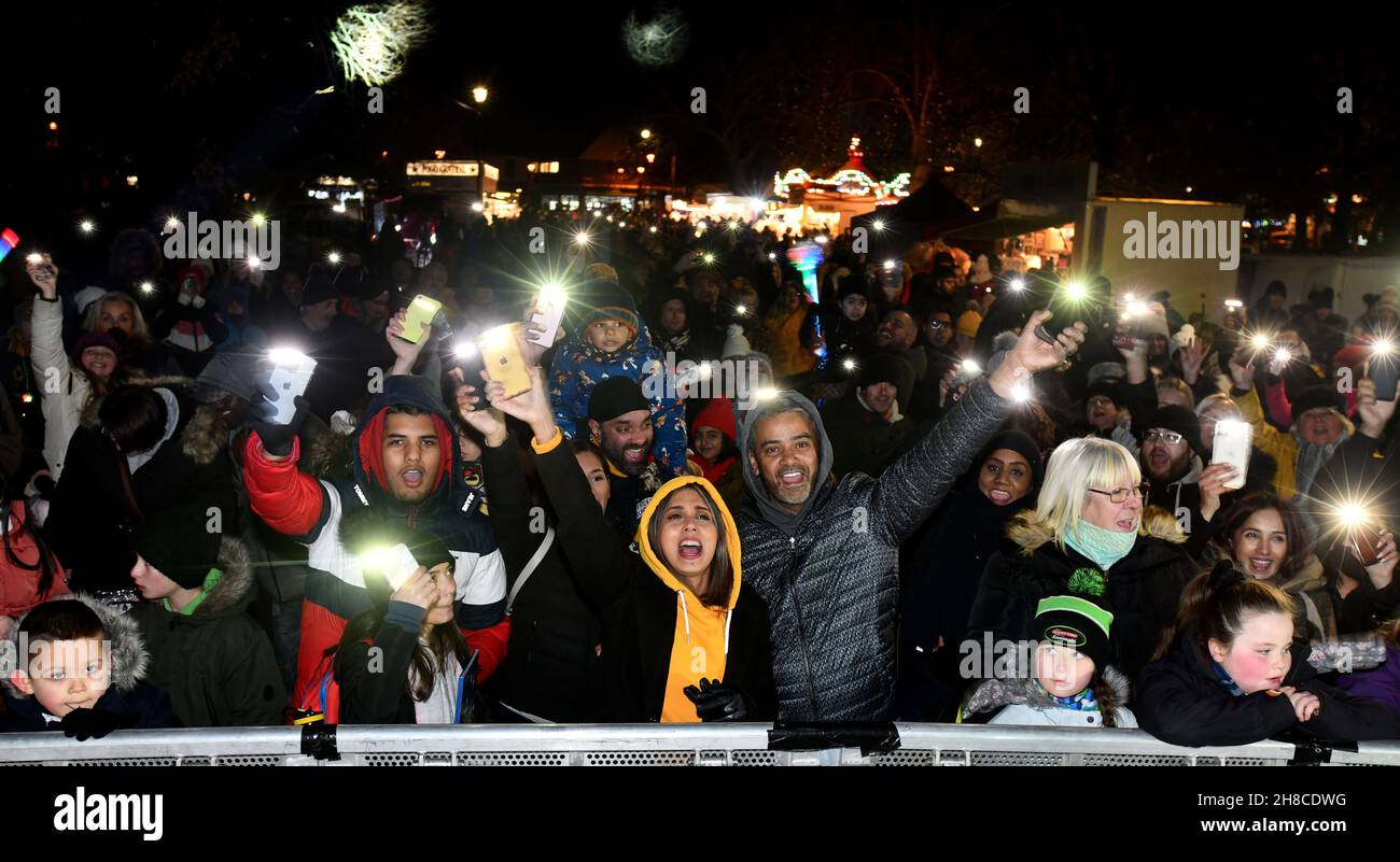 I residenti di spirito della comunità di Natale ondano le luci del telefono cellulare per celebrare le luci di Natale che sono accese a Tettenhall, Wolverhampton, 2021 Foto Stock