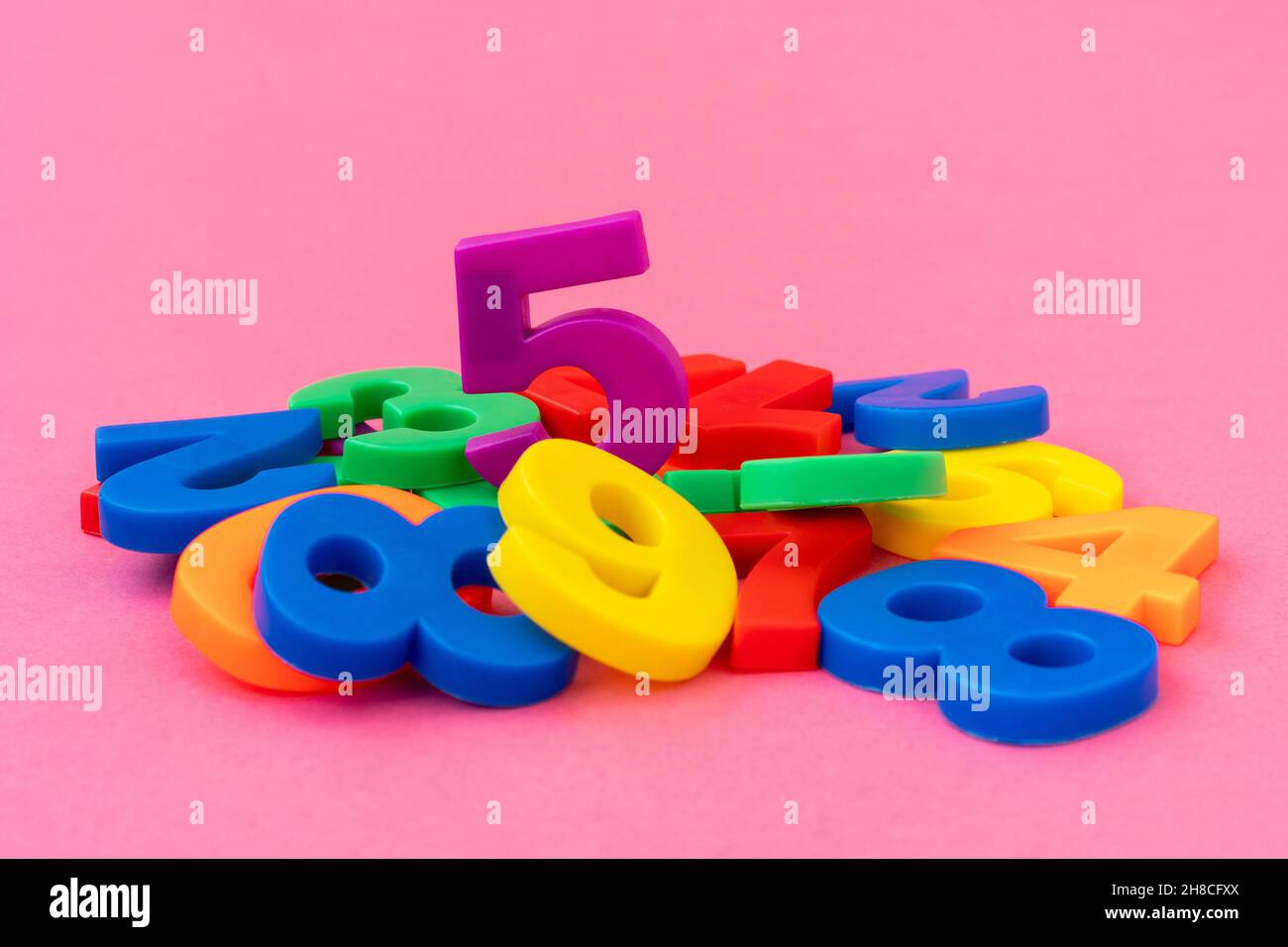 Pila di numeri di plastica colorati. Concentratevi sul numero cinque. Foto Stock