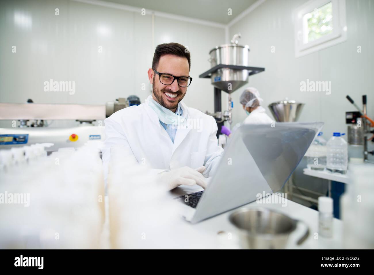 Giovane scienziato felice sta digitando grandi risultati su un portatile. Foto Stock