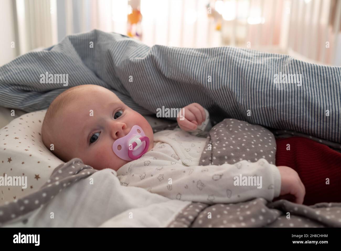 bambina con un succhietto sul letto al mprning Foto Stock