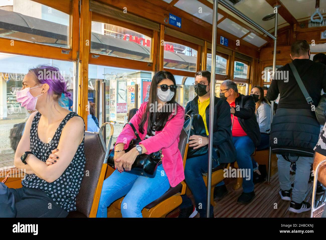 Lisbona, Portogallo, affollano i passeggeri seduti, all'interno, con maschere sulla storica funivia, tram 28 lisbona, tram d'epoca Foto Stock