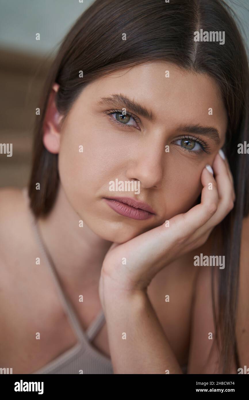 Donna disprezzata che si appoggia la guancia a mano e che guarda avanti Foto Stock