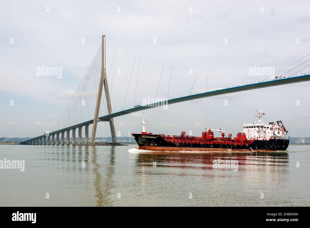 La petroliera chimica 'Stolt Sandpiper' passa sotto il ponte della Normandia in Francia, navigando lungo la Senna sotto un cielo nuvoloso. Foto Stock