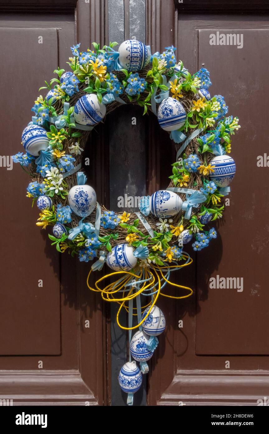 Una corona ornata di fiori, con baubles di porcellana blu e bianco, appesa su una porta di legno marrone nella medievale Golden Lane del Castello di Praga Foto Stock
