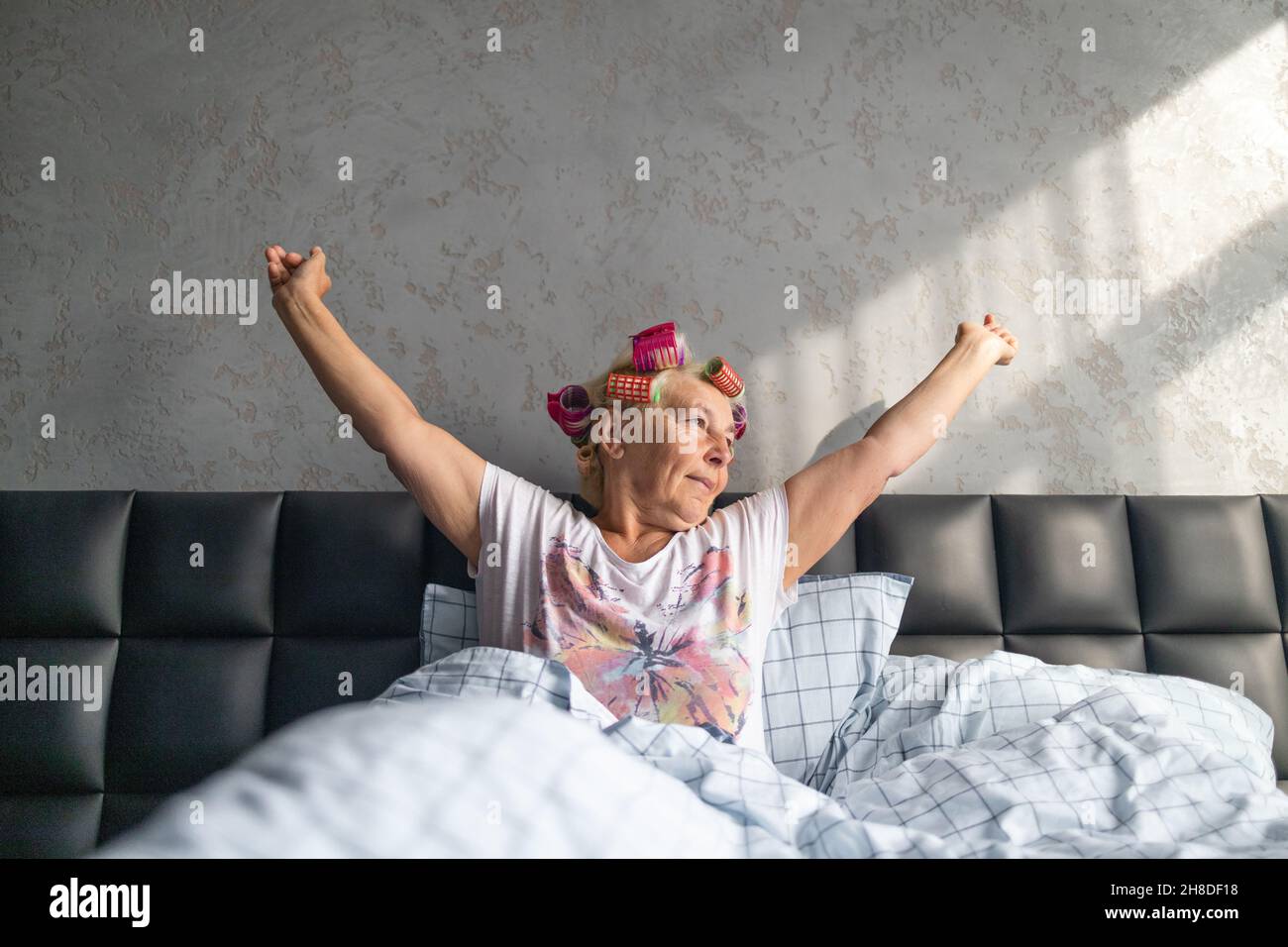 Risveglio precoce, mancanza di sonno sufficiente, sonno eccessivo. Donna di mezza età che sbadigia presto al mattino coperto di coperta bianca sul letto di casa Foto Stock