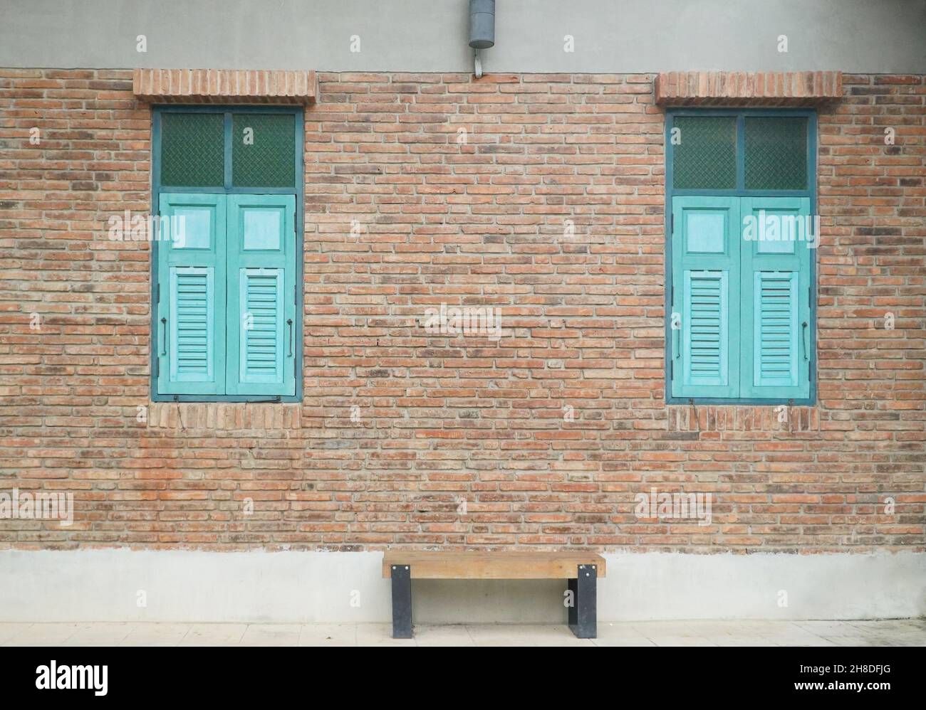 Edificio in mattoni con finestre e panchine in legno blu Foto Stock