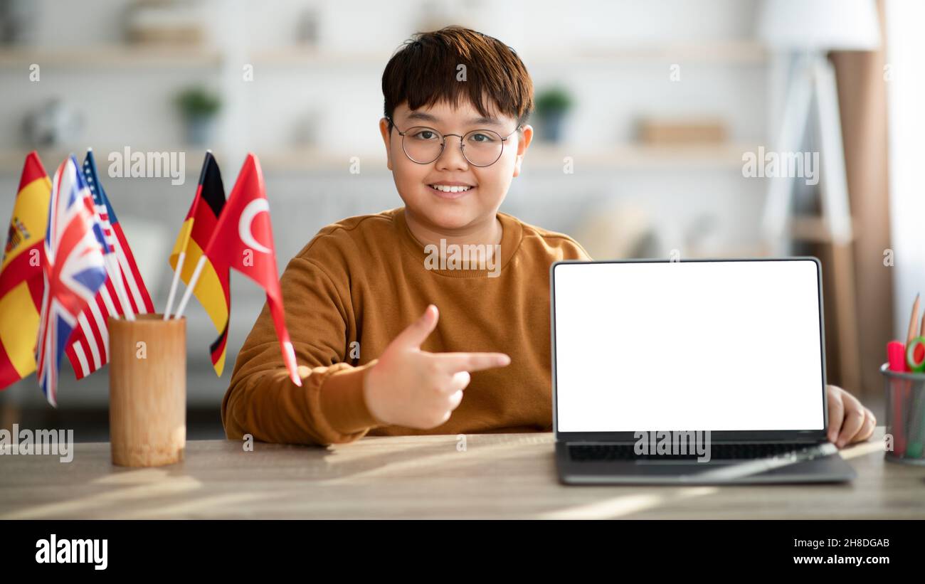 Positivo ragazzo asiatico chubby puntamento portatile con schermo vuoto Foto Stock