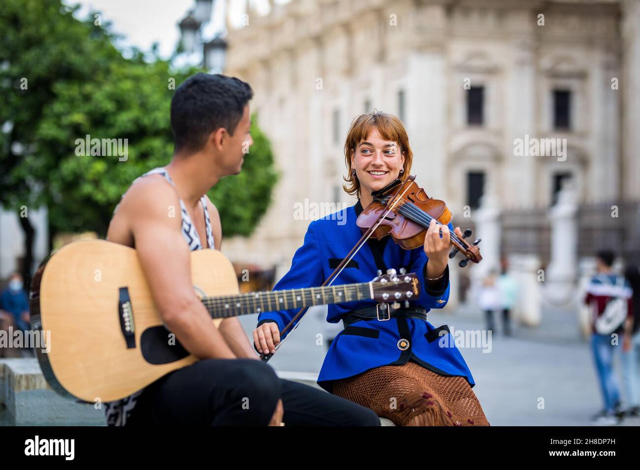I musicisti si accoppiano giocando e divertendosi per strada. Gruppo multietnico. Foto Stock