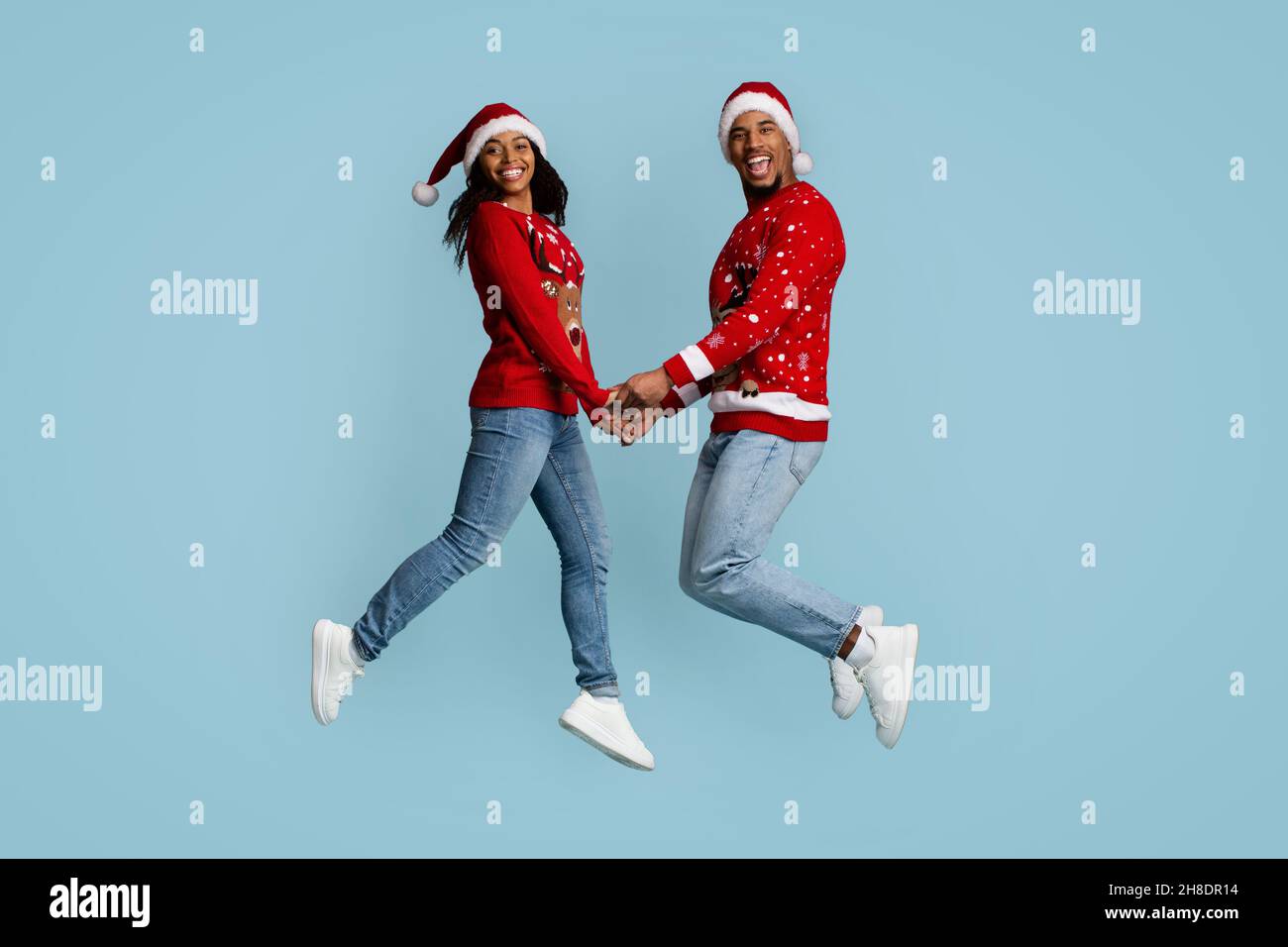 Amorevole coppia nera in Babbo Natale cappelli saltando insieme Foto Stock