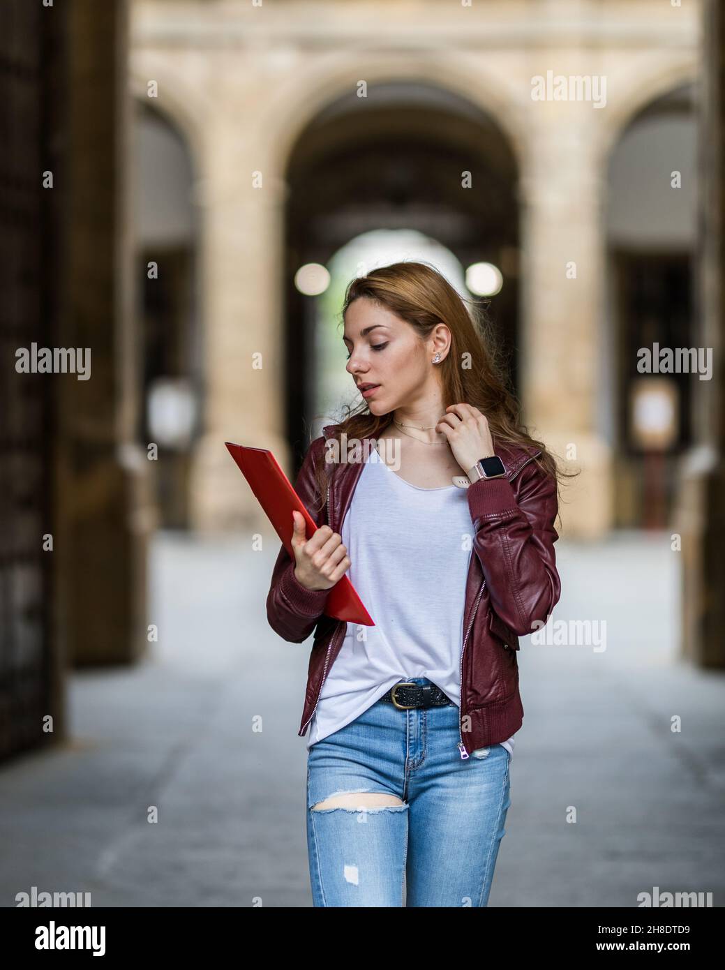 Giovane ragazza casual college andare a classe con una cartella rossa Foto Stock