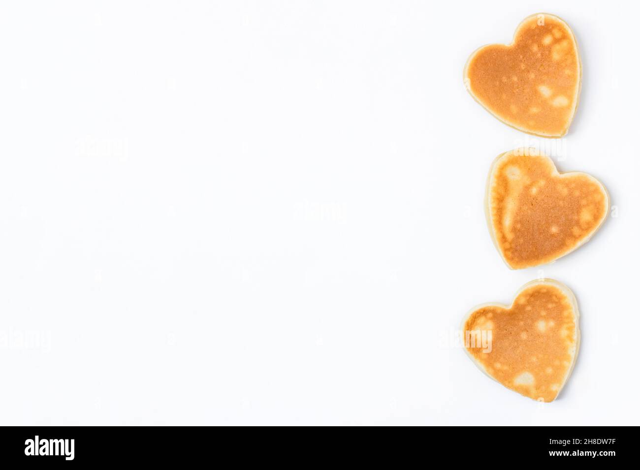 Colazione creativa per San Valentino. Frittelle a forma di cuore isolate su sfondo bianco. San Valentino sfondo giorno. Vista dall'alto. Disposizione piatta. Copia spa Foto Stock