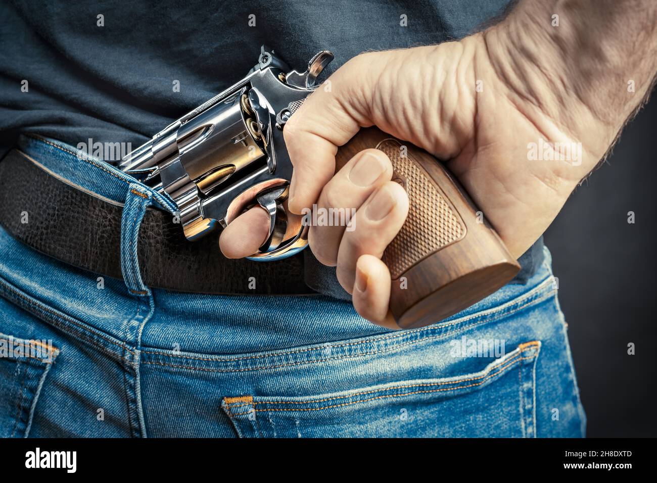 uomo che nasconde un revolver dietro la schiena Foto Stock