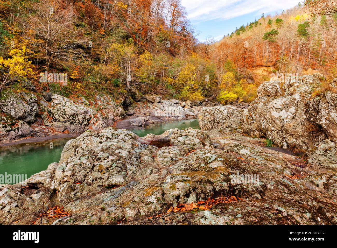 le rive rocciose di granito di un fiume di montagna e la foresta d'autunno Foto Stock