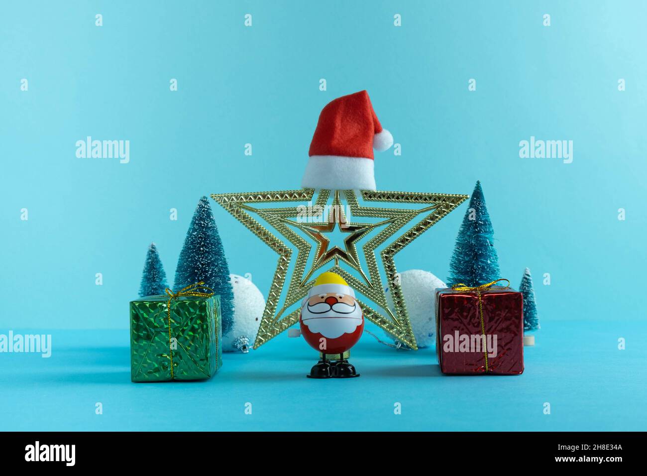 Babbo Natale, un regalo e un albero di Natale in inverno cappelli su uno sfondo blu. Stella sullo sfondo. Concetto di nuovo anno. Buon Natale. Felice nuovo Foto Stock