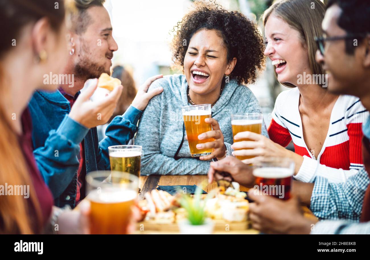 Amici multirazziale bere birra al birrificio pub giardino - amicizia genuina stile di vita concetto con ragazzi e ragazze che godono di happy hour cibo insieme Foto Stock