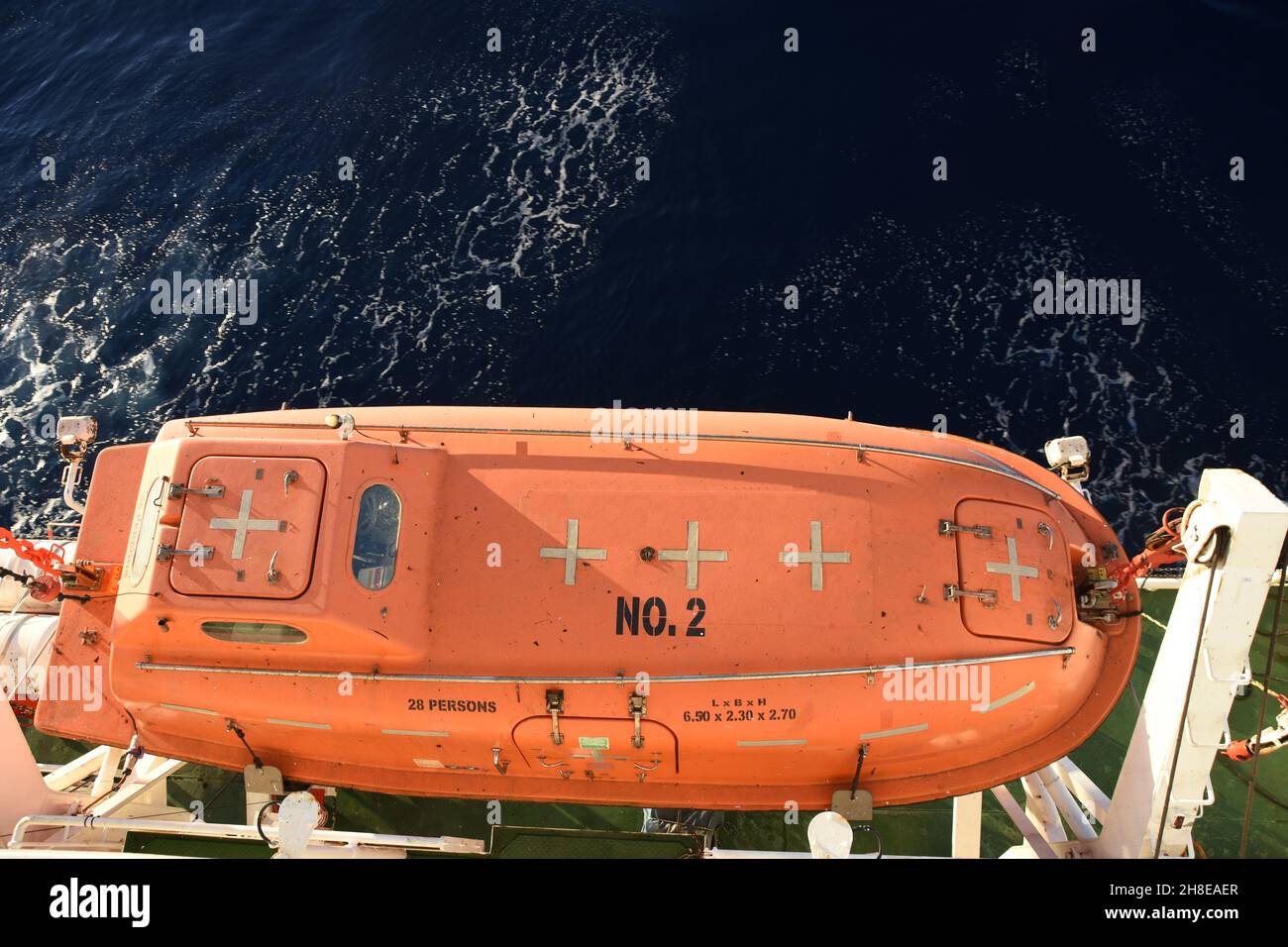 Vista dall'alto sulla Life Boat color arancione con adesivi a nastro riflettente fissati con davit e ganci di sicurezza. Foto Stock