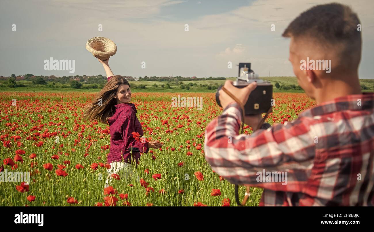 uomo e donna che hanno una data romantica in campo di fiori di papavero con fotocamera, fotografando Foto Stock