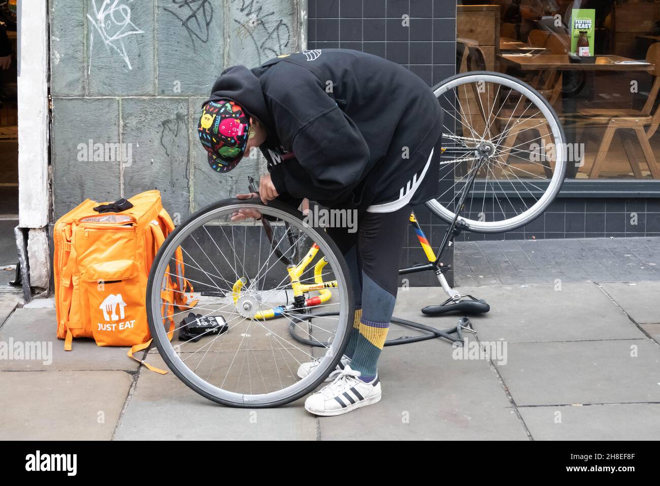 Una persona di consegna della bici di Just Eat che ripara un problema con il pneumatico della bicicletta a Liverpool Foto Stock