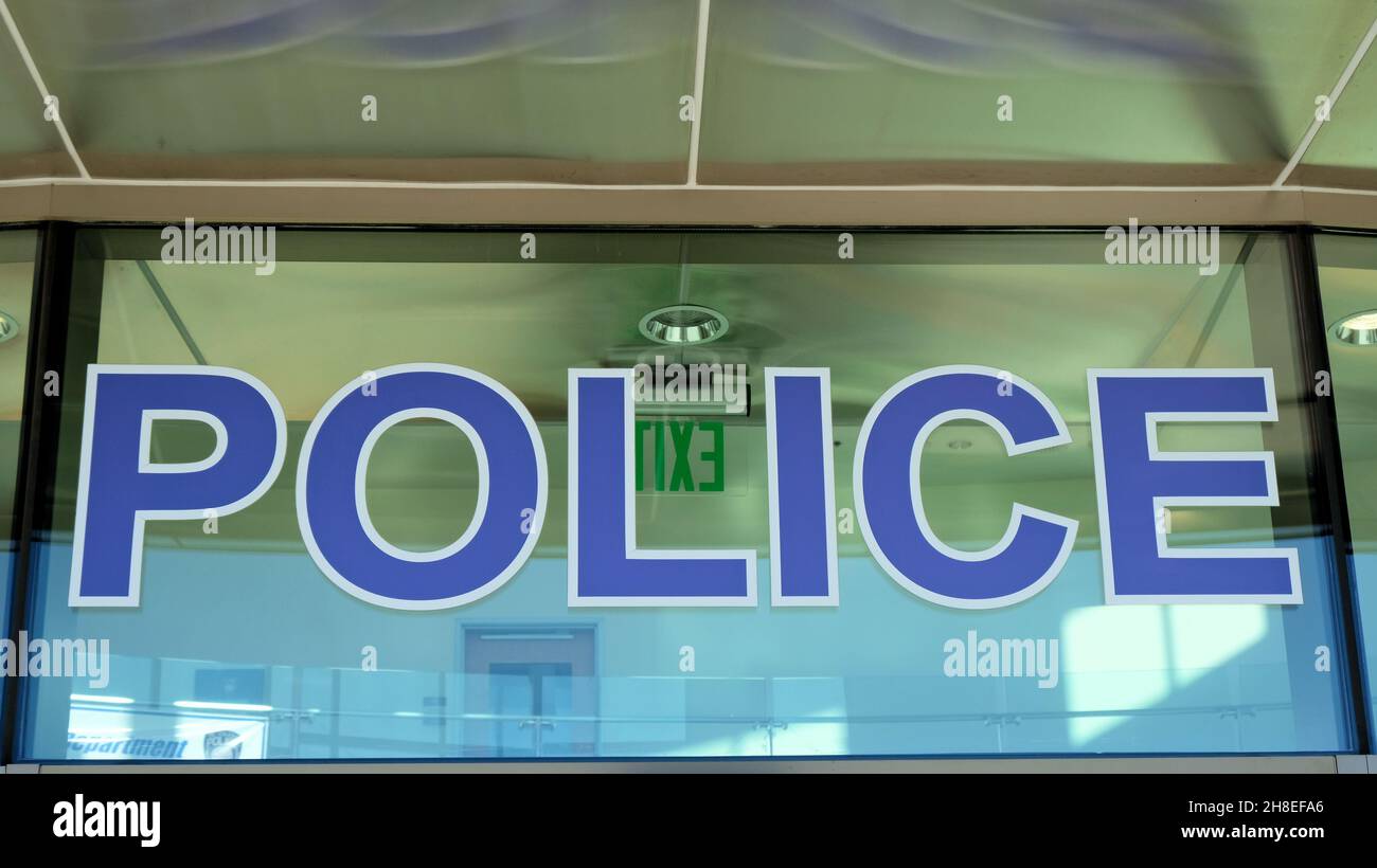 La parola POLIZIA in lettere maiuscole blu su un vetro sopra l'ingresso principale al El Cajon, sede del dipartimento di polizia della California. Foto Stock