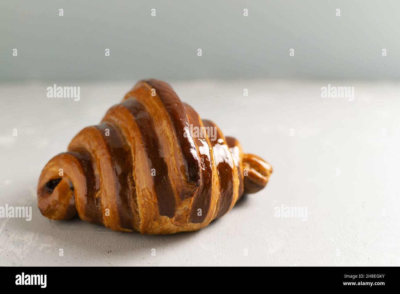 Sul tavolo si trova un croissant alla francese appena appoggiato con ripieno di cioccolato. Deliziosi pasticcini francesi. Spazio di copia. Foto Stock
