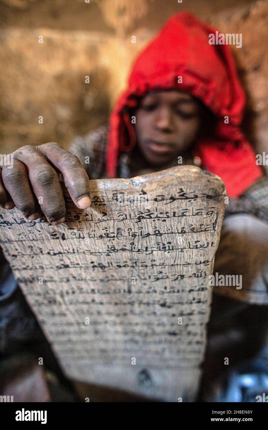 Ragazzo in una scuola coranica siediti di fronte a tavolette di legno, recitando versi coranici, ora dopo ora, giorno dopo giorno a Timbuktu, Mali, Africa occidentale. Foto Stock