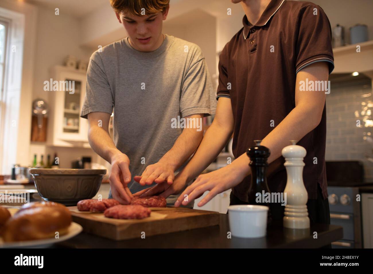 Ragazzi adolescenti che fanno polpettine di hamburger in cucina Foto Stock