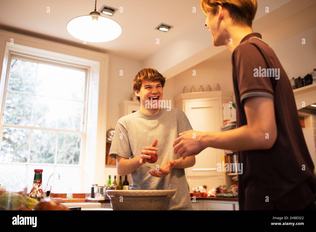 Ragazzi adolescenti felici che fanno polpettine hamburger in cucina Foto Stock