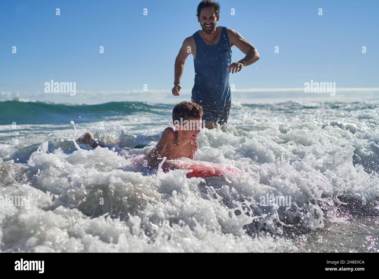 Buon padre e figlio body boarding in mare soleggiato surf Foto Stock