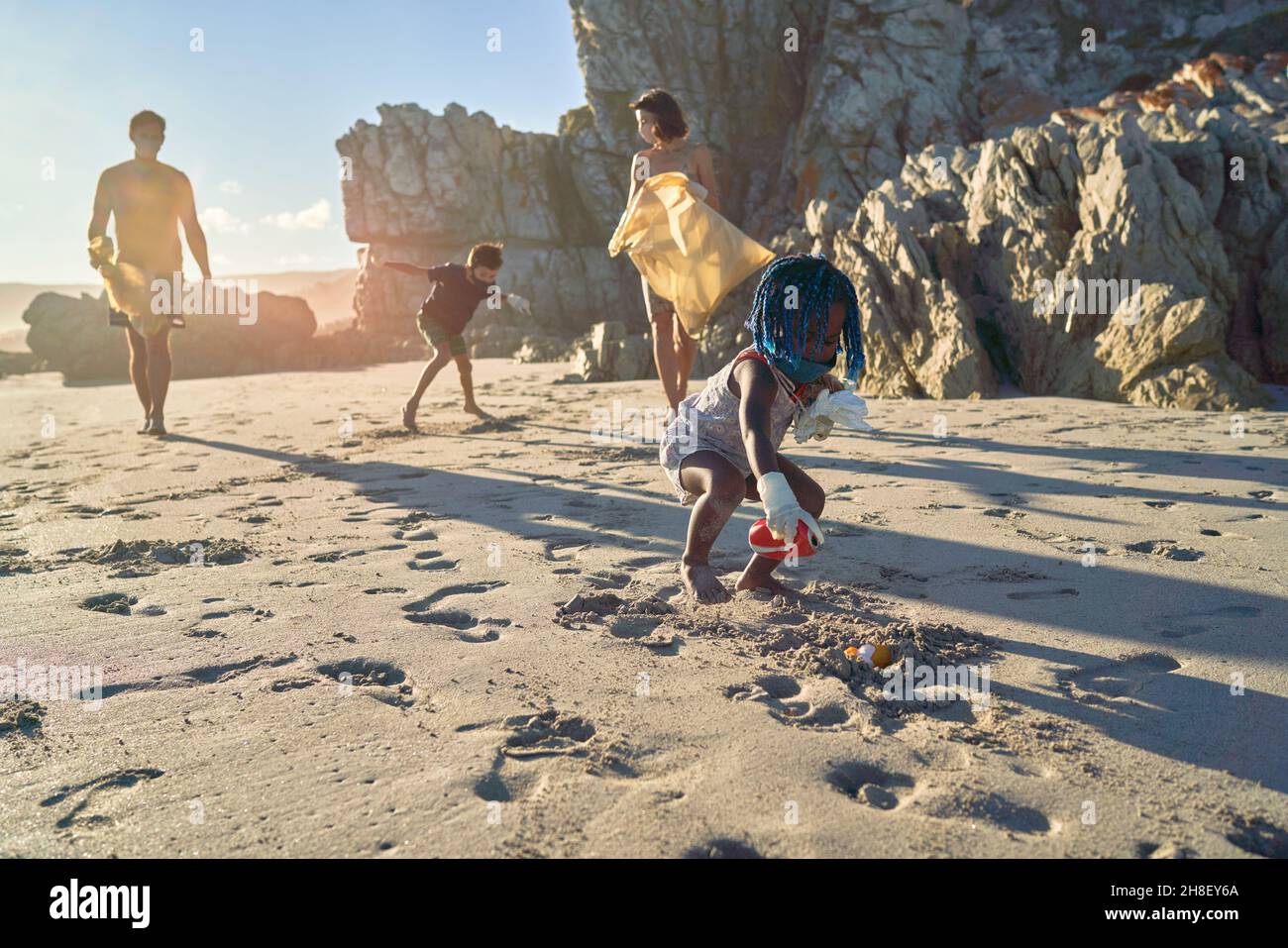 Famiglia volontariato raccogliere rifiuti su spiaggia soleggiata Foto Stock