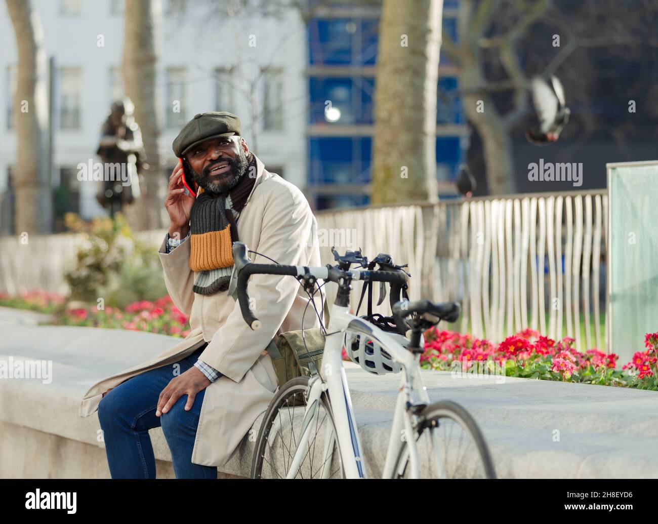 Uomo d'affari con bicicletta che parla sullo smartphone nel parco cittadino Foto Stock