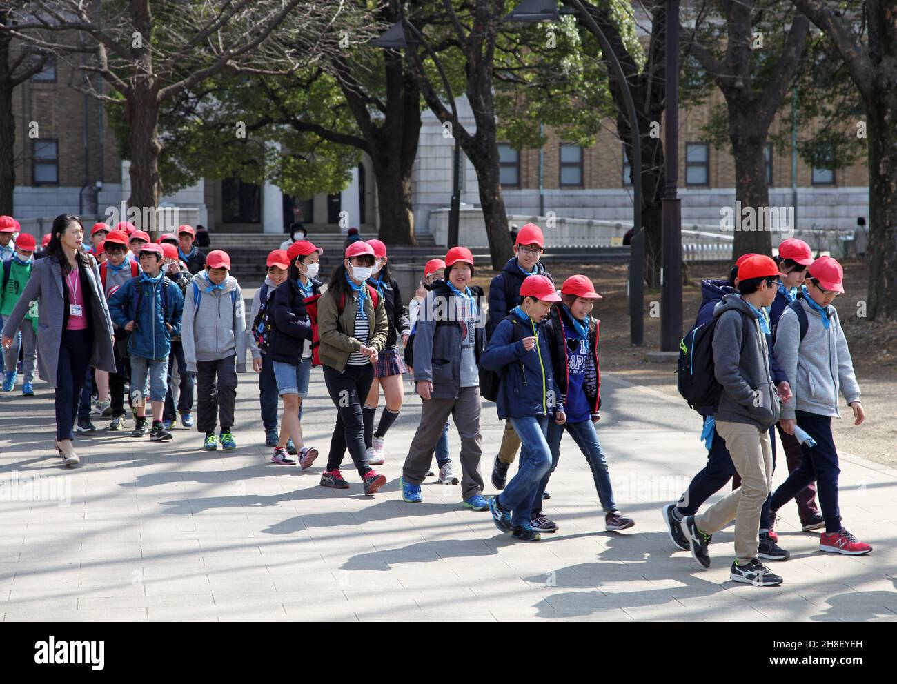 Un gruppo di bambini con insegnante in partenza dal Museo Nazionale di Tokyo in Ueno Park, Tokyo indossando abiti casual e berretti rossi. Foto Stock