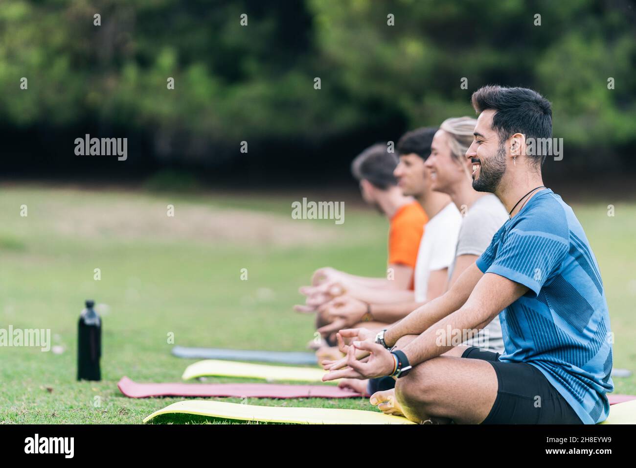 Sorridendo la gente che fa la posa del loto di yoga in un parco Foto Stock