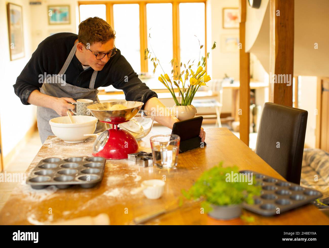 Uomo video chattare e cuocere in cucina disordinata Foto Stock