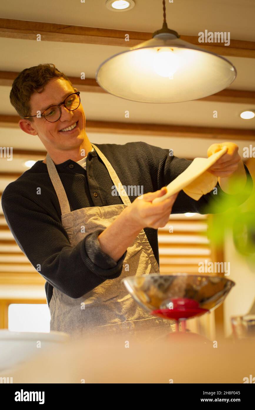 L'uomo felice stretching pizza pasta in cucina Foto Stock