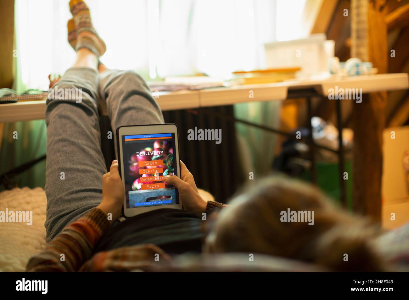 Donna casual in pantaloni da sudore che ordinano cibo da asporto su tablet digitale Foto Stock