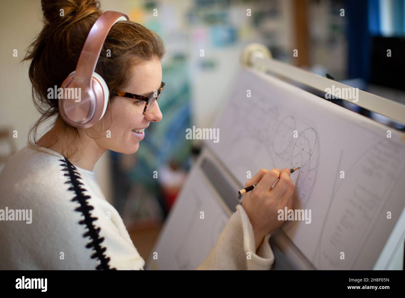 Architetto femminile con cuffie che disegna progetti Foto Stock