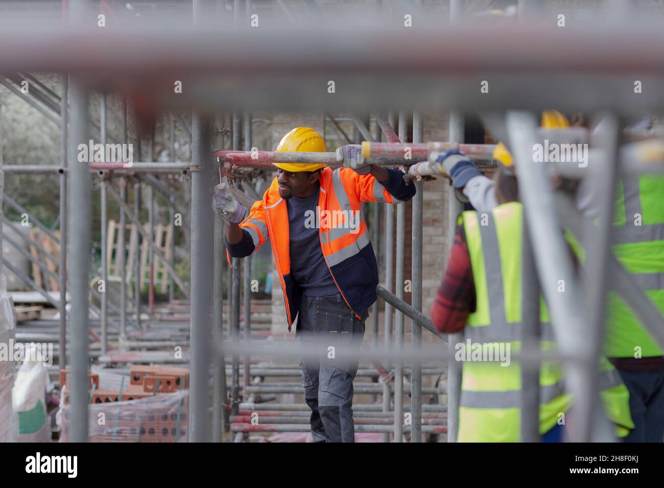 Lavoratore di costruzione maschile che monta impalcature in cantiere Foto Stock